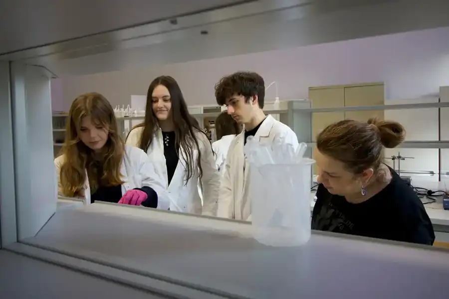 Uczniowie w fartuchach podczas zajęć laboratoryjnych
